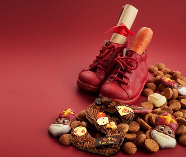 saint nicholas sinterklaas day with shoe, carrot and traditional sweets on red background